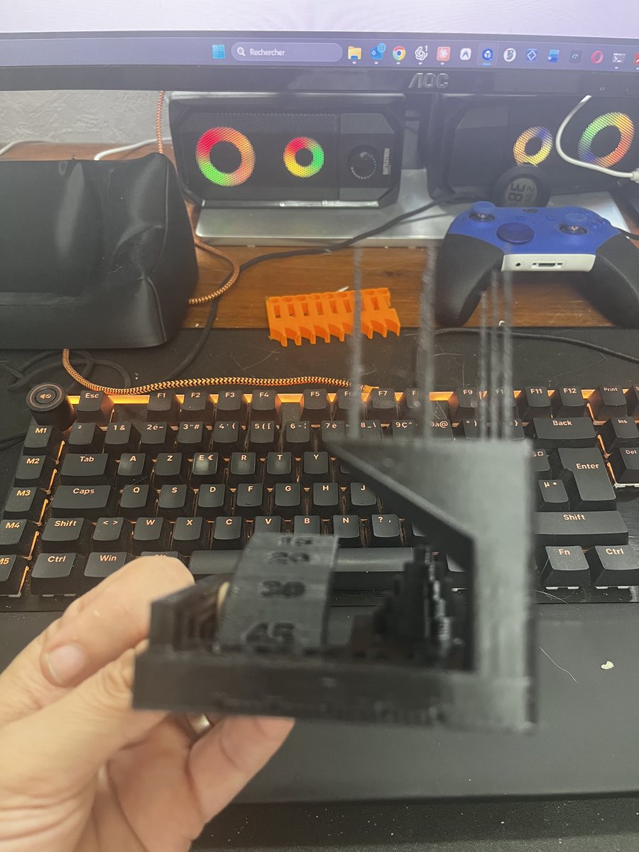 Pièce de test en PETG noir AzureFilm photographiée à contre-jour, fils visibles